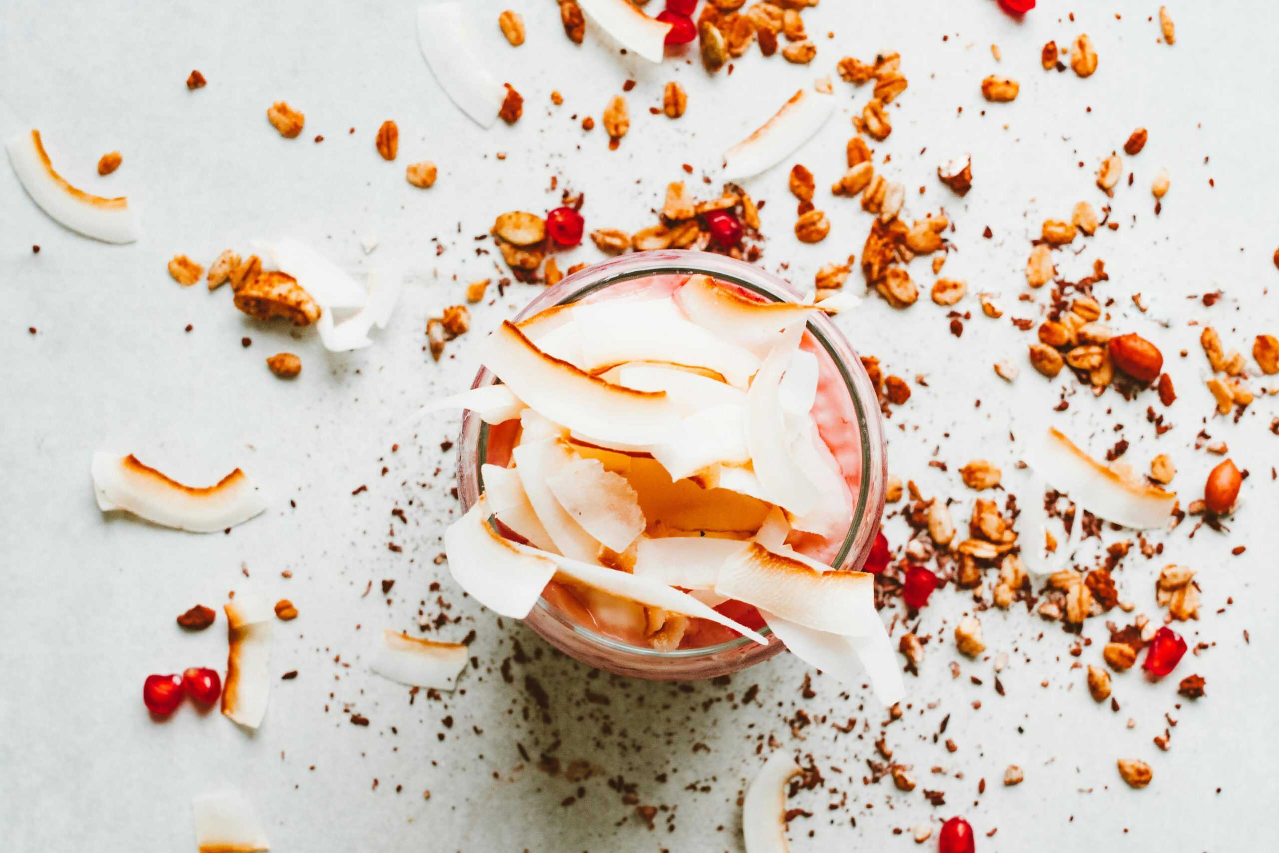 Delicious yogurt parfait topped with coconut flakes, granola, and pomegranate seeds.