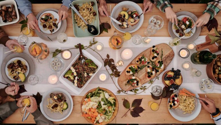 Dinner Party, Fall theme, Overhead shot of a vibrant dining table setup with pasta, salads, and decorative candles, capturing a festive gathering.