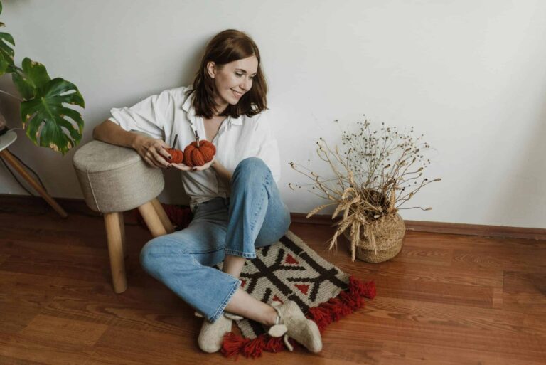 This is a photograph of a woman sitting on the floor. You can declutter your space before hosting fall holiday visitors.