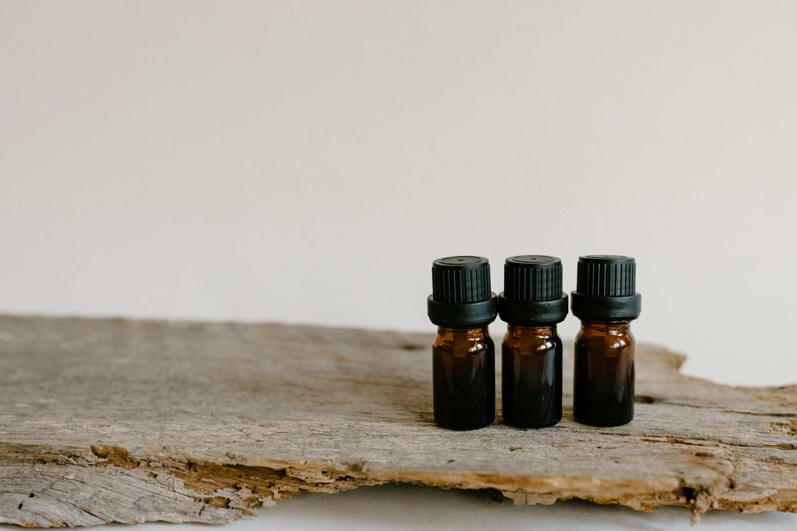 Three essential oil bottles on rustic wood surface, perfect for aromatherapy and natural healing themes.