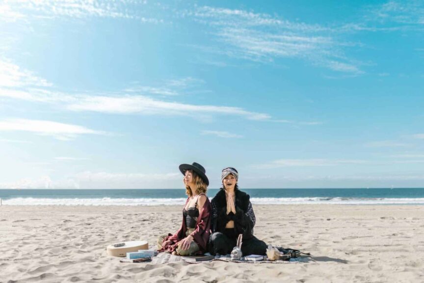 Manifestation, Women practicing meditation and crystal healing on a sunny beach.