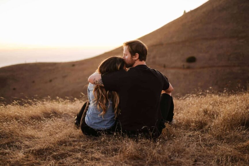 This a photograph of a couple sitting together on a hill. A relationship sabbatical can help a couple from drifting apart.