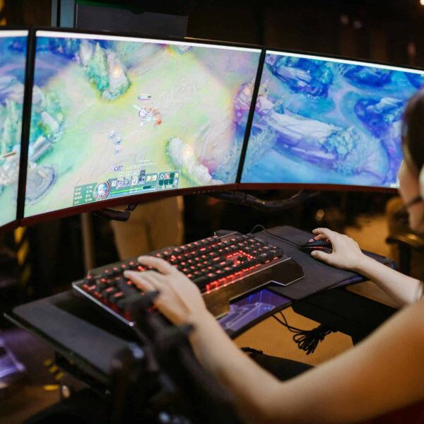 A young woman intently gaming on a multi-screen setup, showcasing vibrant gaming visuals./adult-themed games