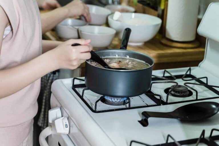 Close-up of a woman stirring soup on a gas stove in a home kitchen. one-pot soup