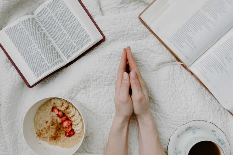 A serene morning scene with a person praying, an open Bible, oatmeal, and coffee. Daily devotion