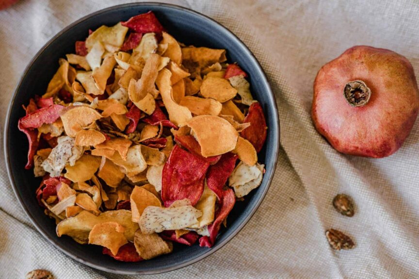 healthy chips, recipes, A stylish presentation of healthy dried fruit chips in a bowl with a pomegranate on textile background.