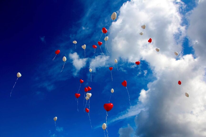 This is a photograph of heart-shaped balloons floating in the sky. It is important to consider feelings when considering ethical non-monogamy.