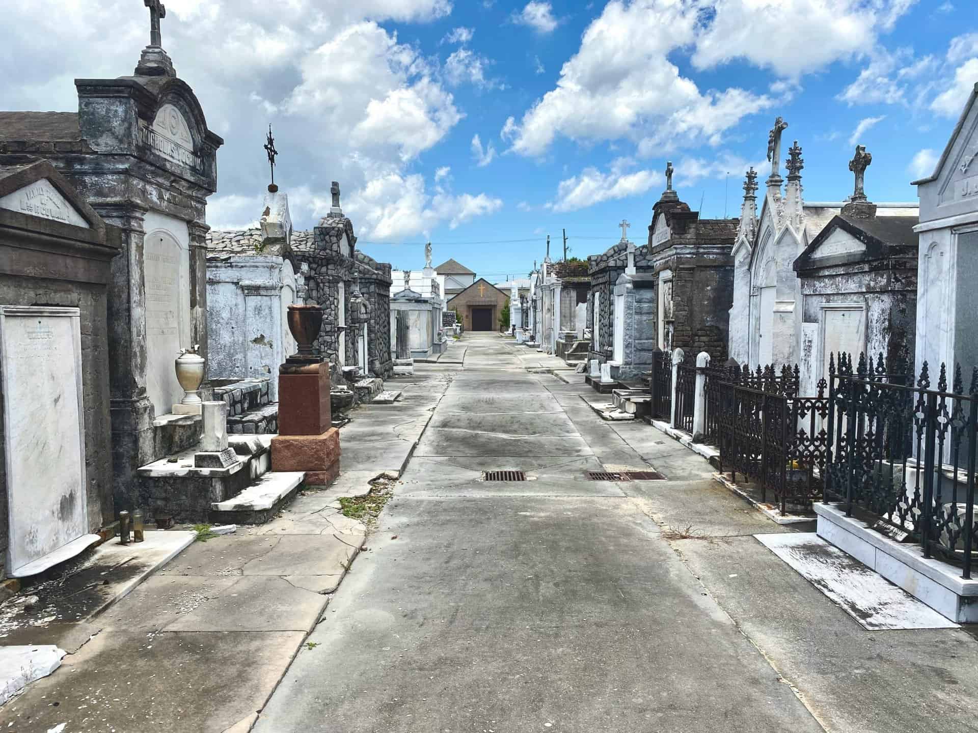 View of historic cemetery tombs and vaults under a vibrant blue sky.