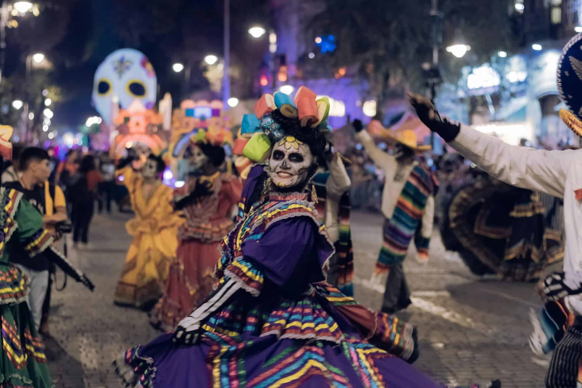 Colorful Day of the Dead parade with costumes and face paint in vibrant street festivities.