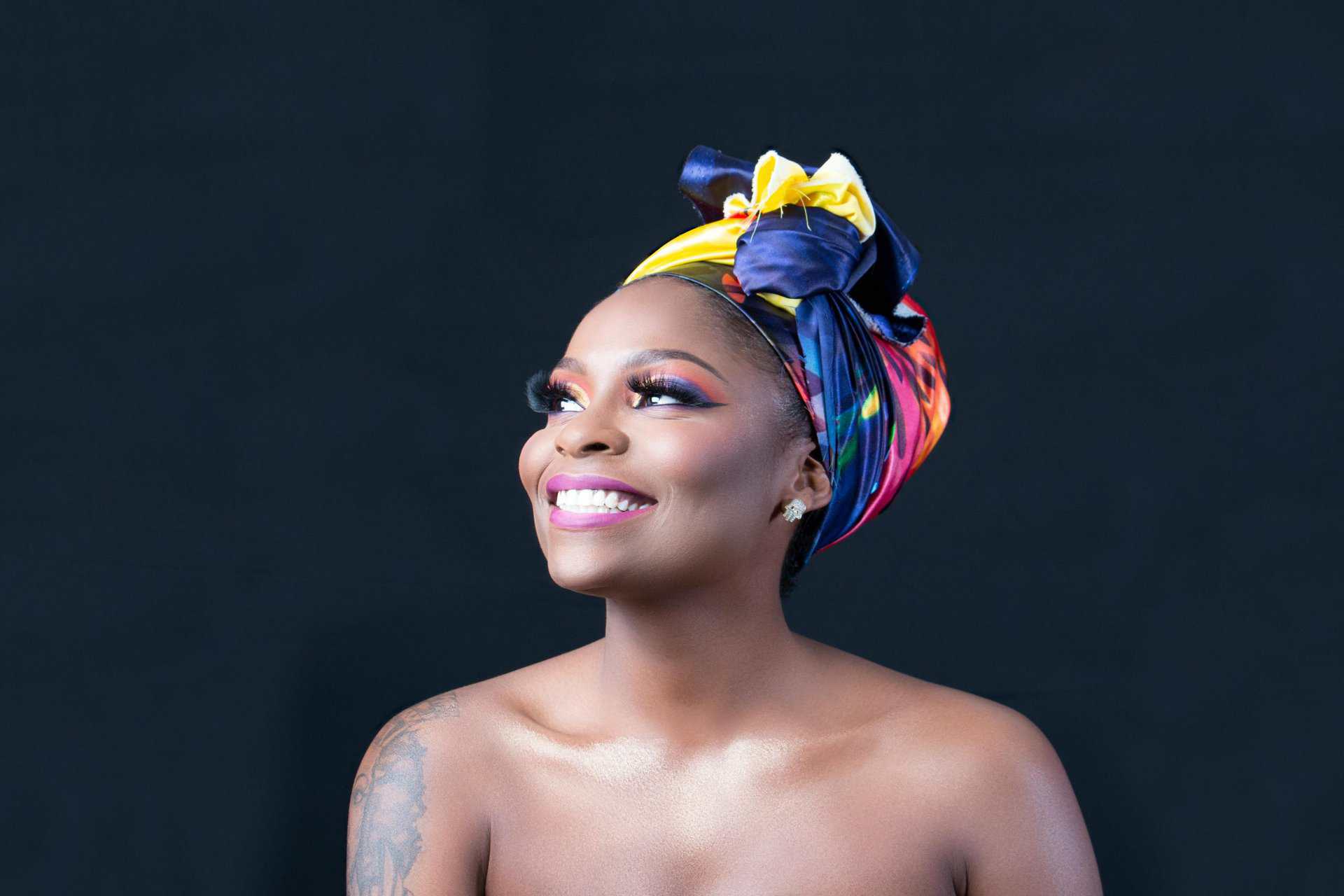 A beautiful portrait of a smiling woman wearing a vibrant headwrap, exuding joy and elegance. Glowing skin from good microbiome, good gut health.