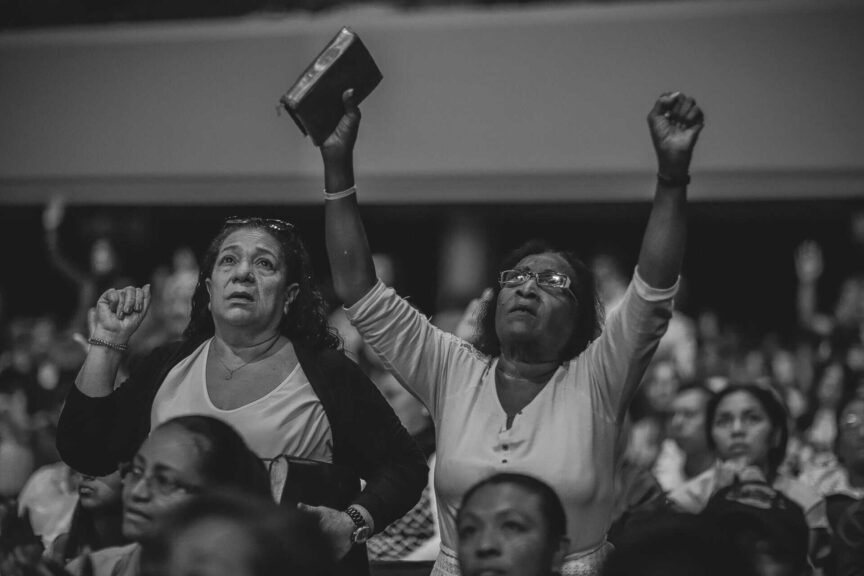 A heartfelt moment of worship in a crowded indoor religious gathering. God With Us