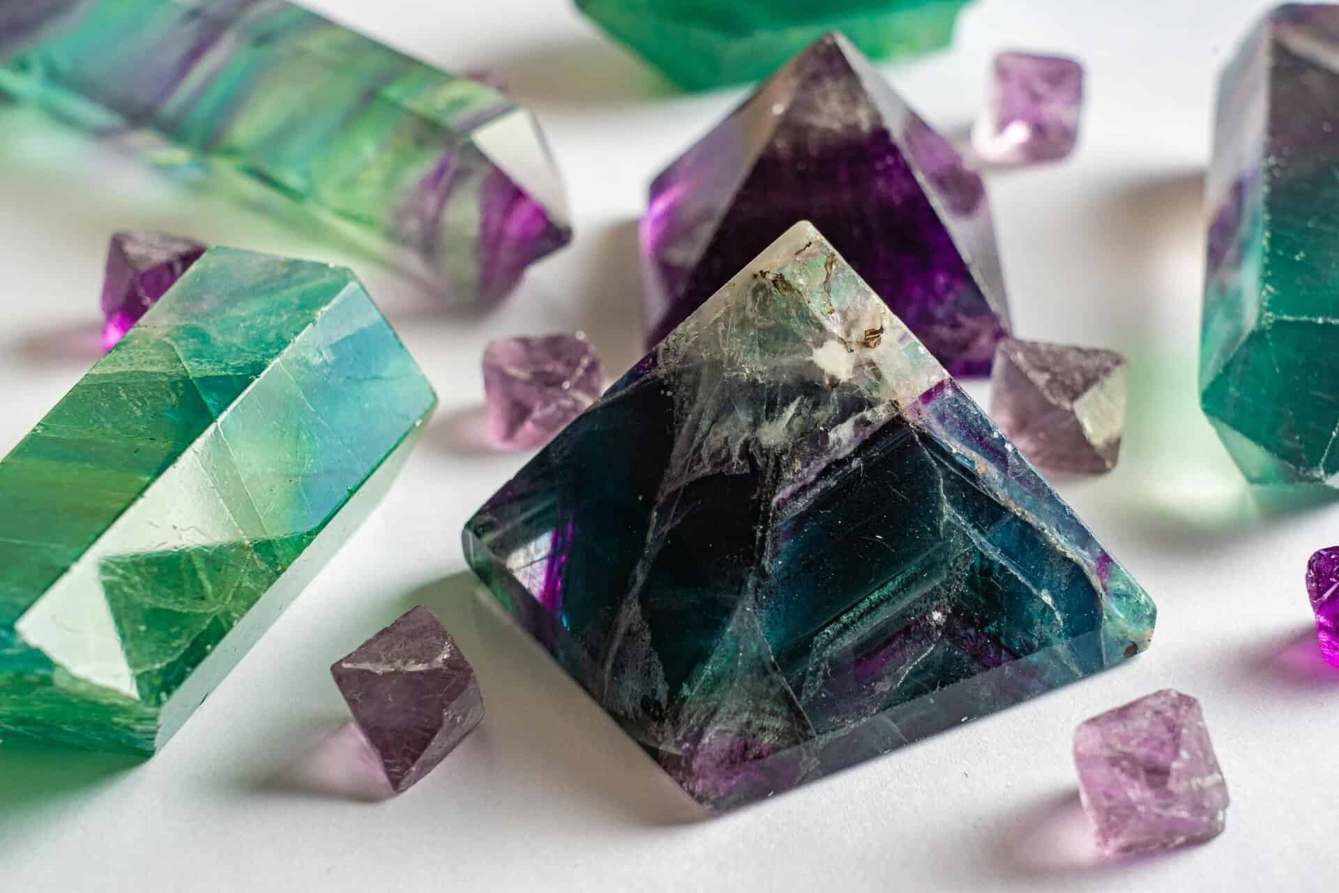 Close-up of colorful fluorite and amethyst crystals in various shapes on a white surface. Tools for cleansing your aura, meditation and ritual.