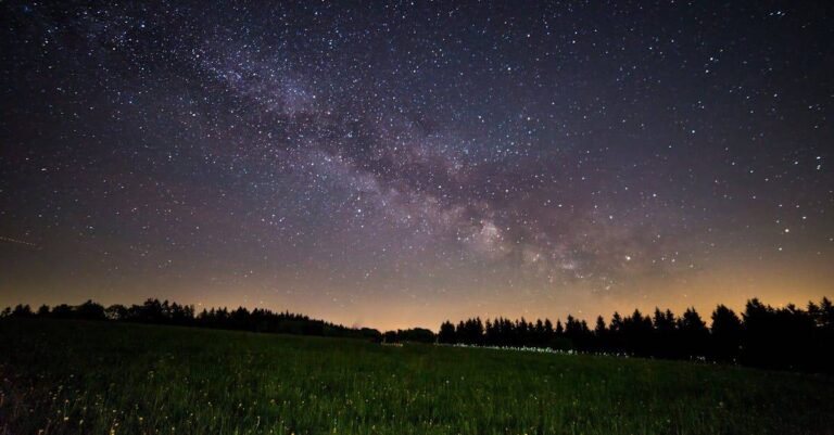 A breathtaking view of a starry night sky over a quiet field, showcasing the Milky Way. planetary returns