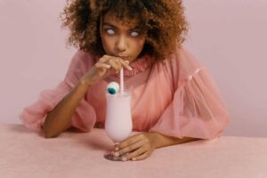 Young woman in a creative Halloween costume sipping a milkshake with a candy eyeball. halloween drinks