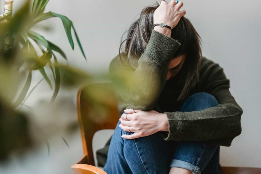 This is a photograph of a woman on a chair expressing sadness. Emotionally haunting someone may be a result of unresolved relationship difficulties.