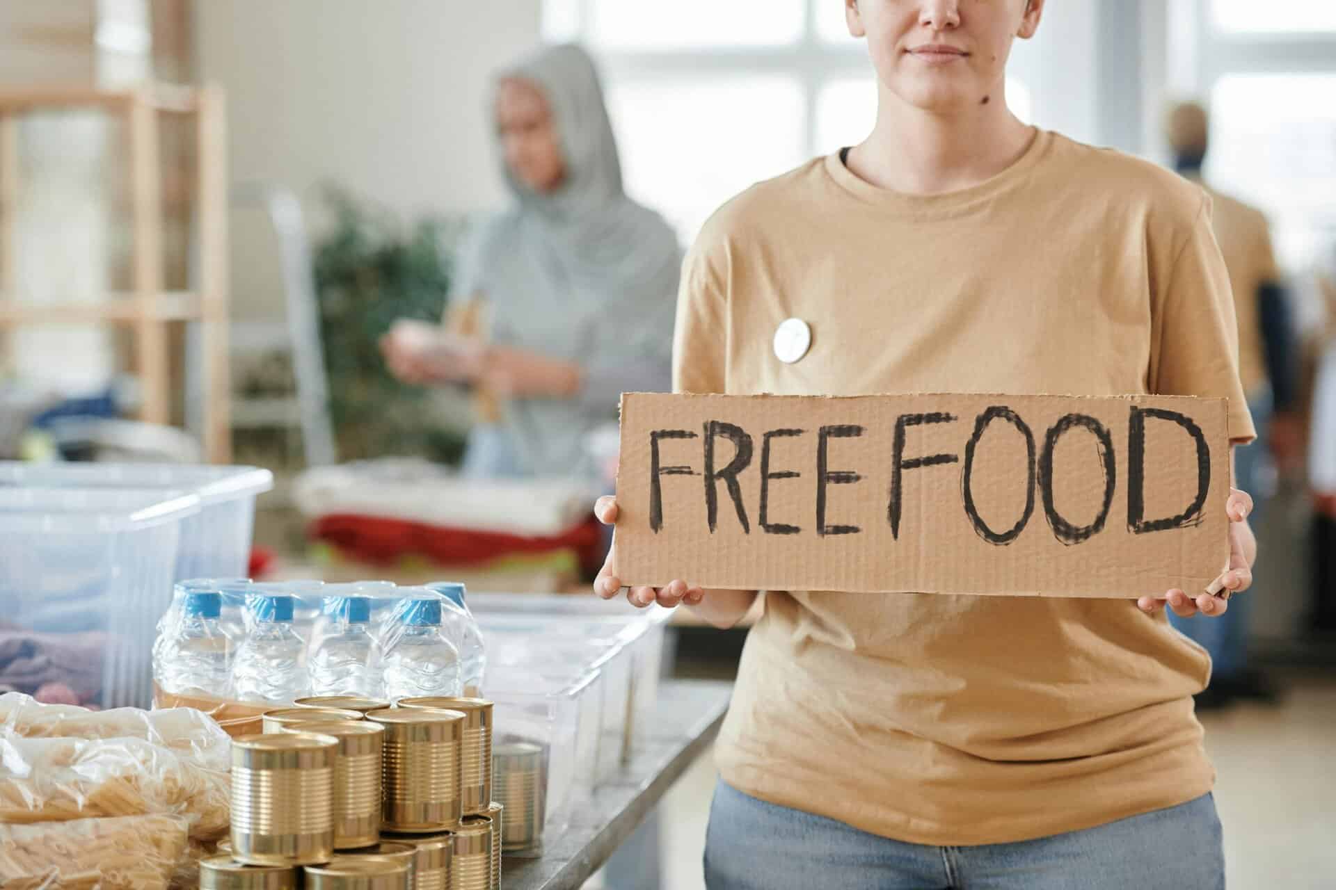 Volunteer holding a free food sign at a donation center, promoting charity and aid. Families depent on your local food bank.