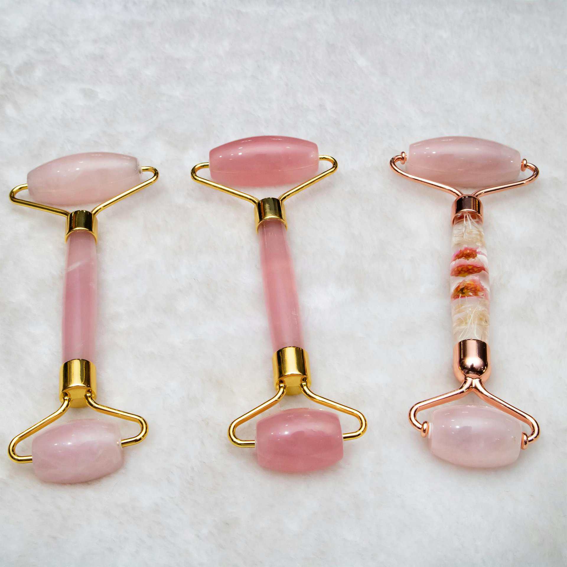 Three pink jade face rollers elegantly arranged, showcasing skincare luxury. Lymphatic draining.
