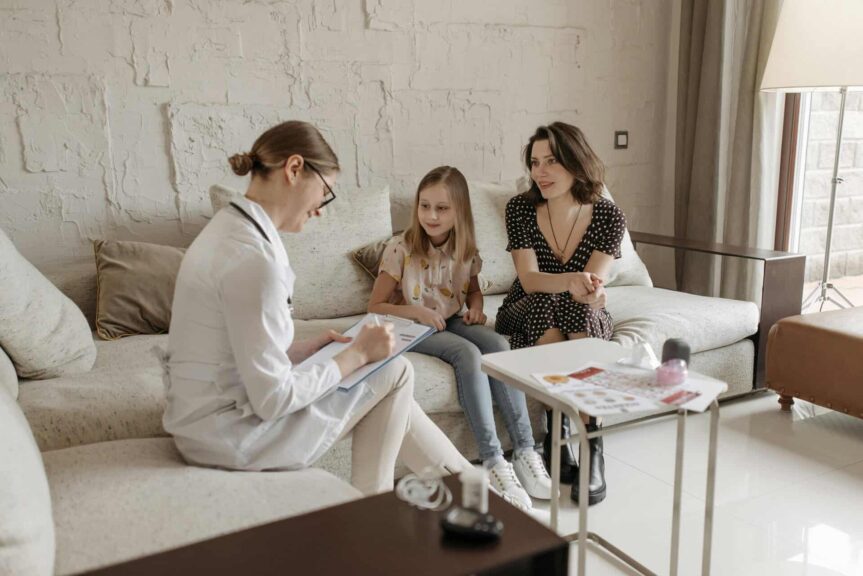 A doctor consults with a mother and daughter in a cozy indoor setting, children's emotional wellness