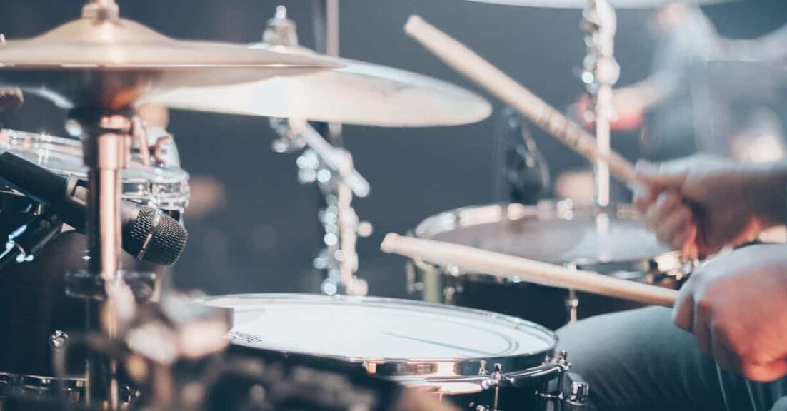 Close-up of a drummer performing on stage with focus on drum set and drumsticks. new single. Playlist