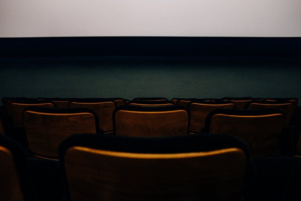 An empty auditorium with wooden seats facing a blank theater screen.
Ice Cream Man