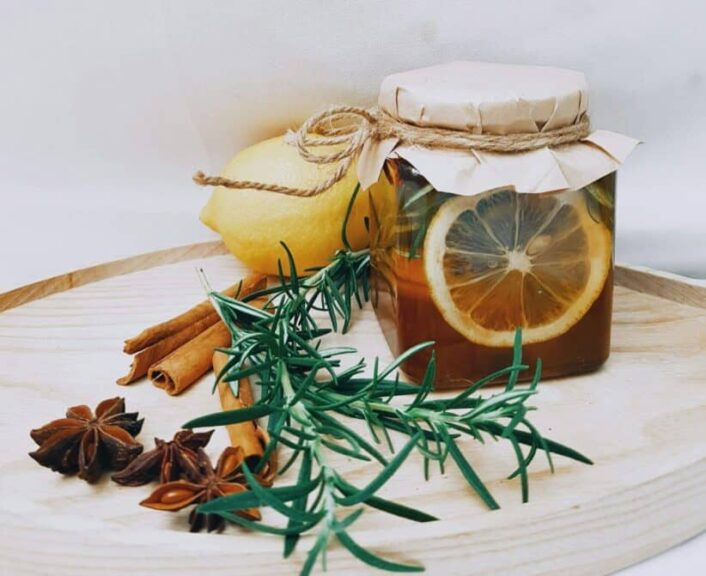 Artistic arrangement of lemon, herbs, and honey jar for DIY herbal tea.