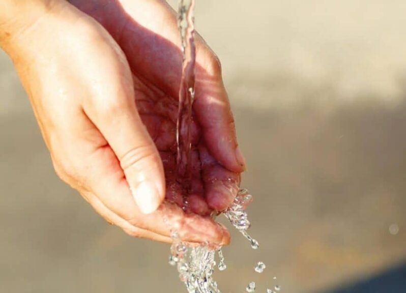 Close-up of hands catching flowing water outdoors, symbolizing freshness and purity and the sign of Aquarius.