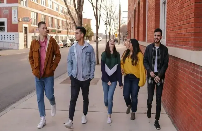 five people walking on a sidewalk in town