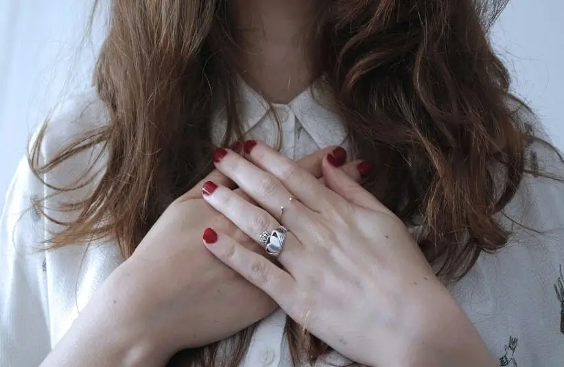 woman with hands crossed on her chest, silver claddagh ring, self acceptance