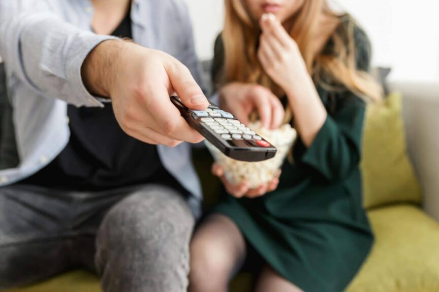 image of A couple enjoying a relaxing movie night, sitting on a sofa with popcorn and a TV remote in November