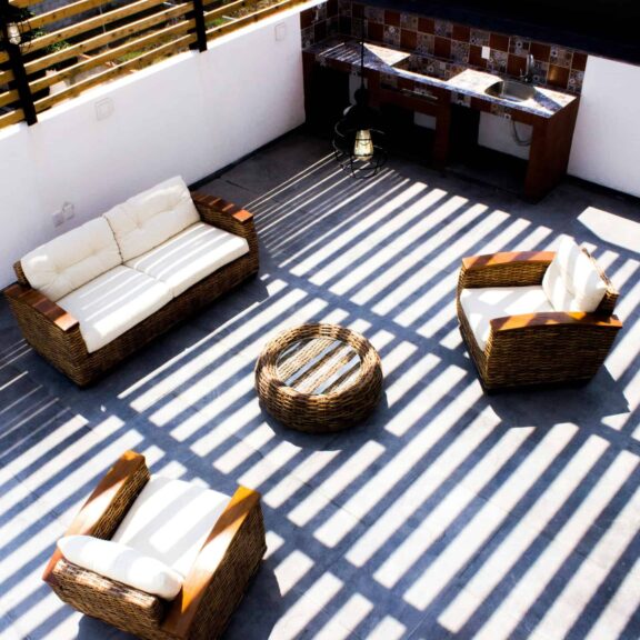 Aerial view of a minimalist outdoor patio with woven furniture casting dramatic shadows.