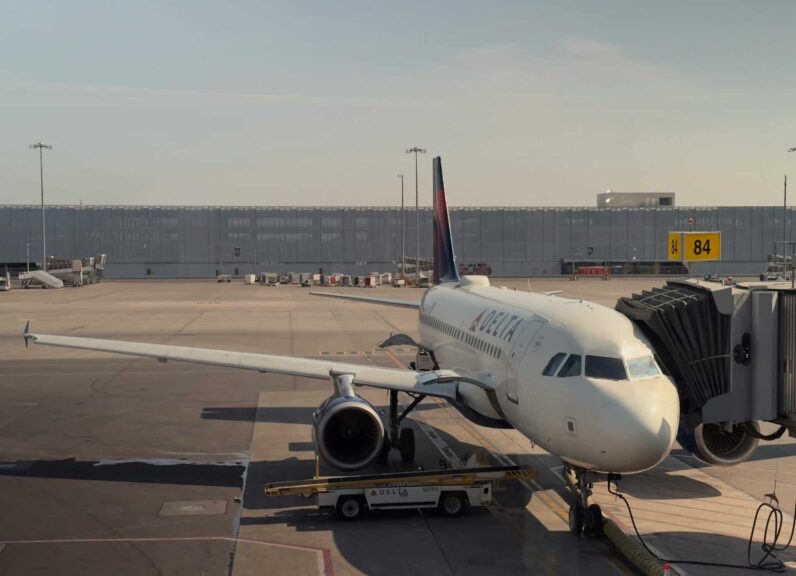 A Delta airplane docked at Montreal's airport gate 84 during daylight. Voted best u.s. airline.