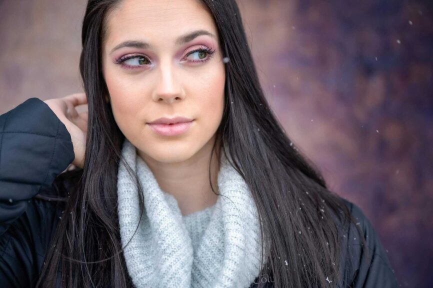 This is a photograph of a woman in a gentle snowfall. Makeup essentials focusing on taking care of skin can help you sparkle in winter.