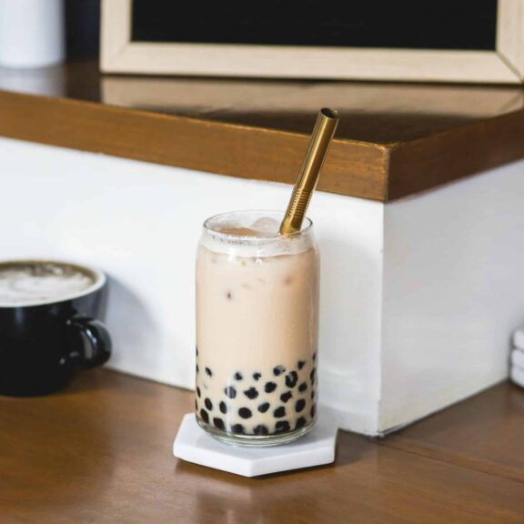 A refreshing glass of iced bubble tea with a metal straw, perfect for a relaxing moment in a cozy café.
