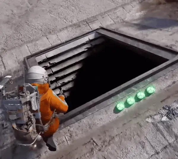 Screenshot of ARC Raiders. Raider in a orange jumpsuit with space helmet and large backpack trying to enter a rolled up bunker door