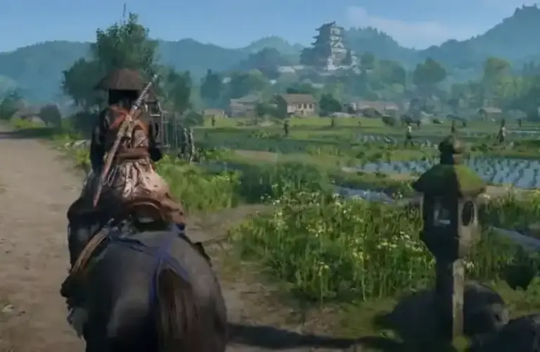 Assassin's Creed Shadows samurai rides on a horse down a rural path, surrounded by lush fields and distant mountains.