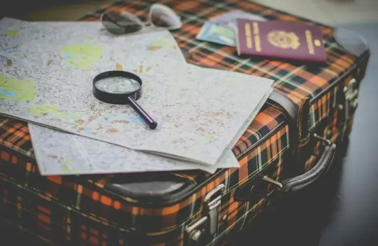 suitcase, maps, passport, & magnifying glass for travel prep,