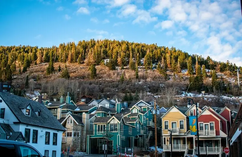 Park City, UT, USA, colorful houses in front of a slope covered in evergreen trees and snow