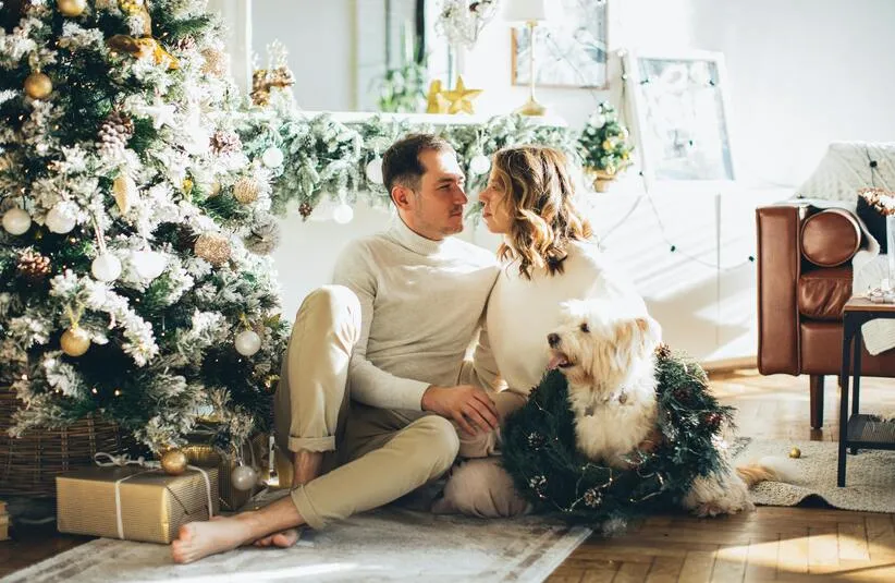 Couple sitting next to their dog by the Christmas Tree. Could be used for a Christmas Card from your pet.