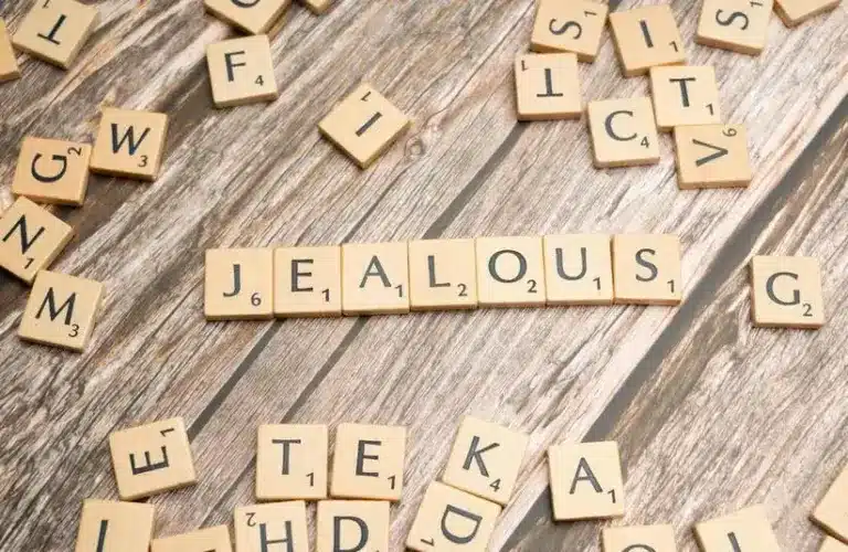 Jealous spelled out in scrabble like tiles. Holiday jealousy can be a lot to navigate