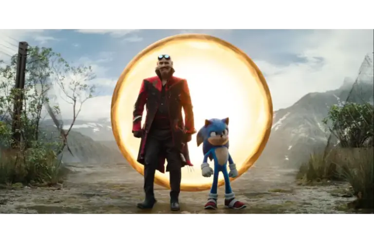 A blue anthropomorphic hedgehog and a man in a black and red coat stand on a dirt road near a glowing golden ring. Mountains and cloudy sky are in the background. Dr. Robotnik (portrayed by Jim Carrey) and Sonic,(portrayed by Ben Schwarz) Courtesy of Paramount Pictures and Sega of America, Inc.