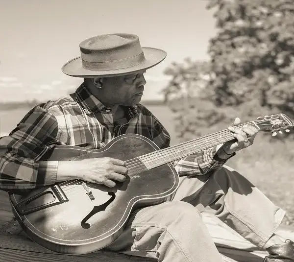 Award-winning blues icon Eric Bibb plays guitar outdoors.