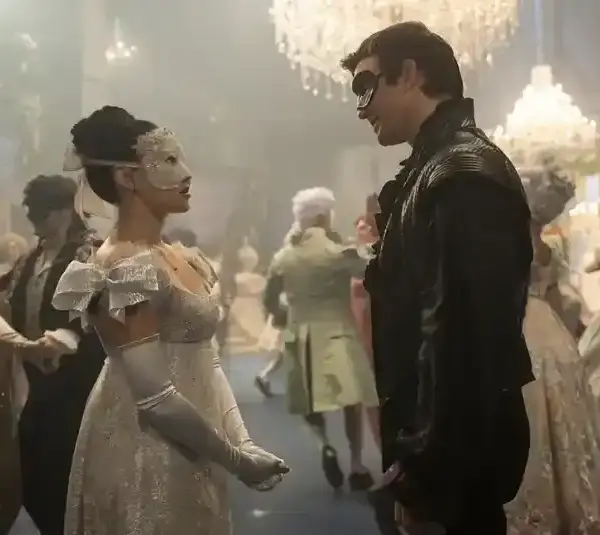 TV couples in elegant, vintage attire and masks stand facing each other at a lavish masquerade ball. Chandelier-lit ambiance, other couples dance. Romantic tone.