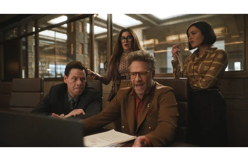 Ike Barinholtz, Seth Rogen, Kathryn Hahn, and Chase Sui Wonders in The Studio (2025) in an office appear surprised and focused on a laptop screen. One person is seated, gesturing animatedly. The tone is tense and engaged.
