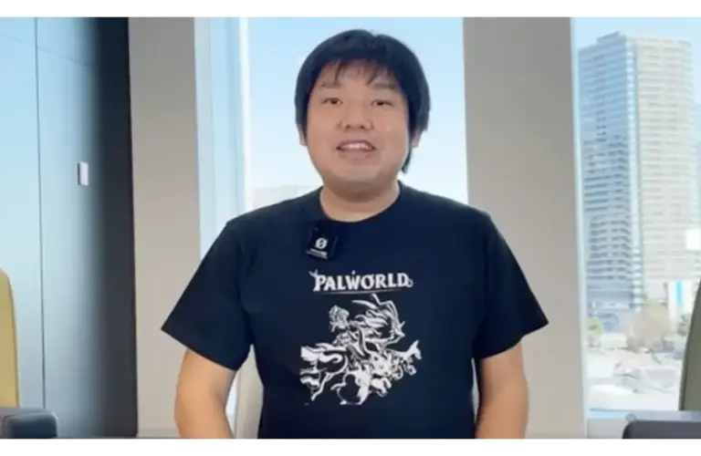 Poketpair CEO, Takuro Microbe, in a Palworld t-shirt, smiles in a bright office with urban buildings visible through large windows. The atmosphere is casual and friendly.