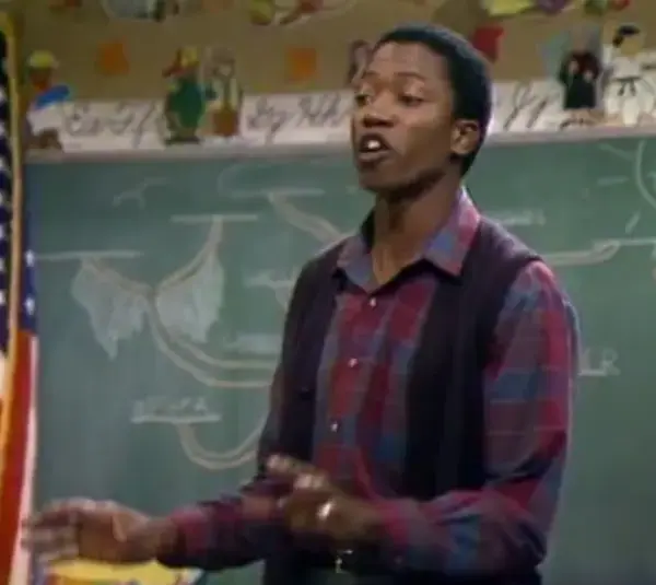 T.K. Carter in a plaid shirt is speaking passionately in front of a chalkboard with diagrams during an episode of "Punky Brewster" called "The Search" (1984).
