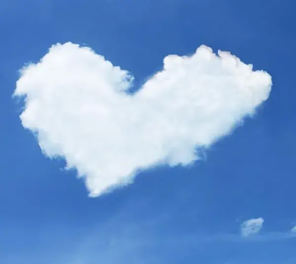 image of A fluffy white cloud shaped like a heart floats against a clear blue sky, evoking a sense of calmness, whimsy, and Valentine's Day