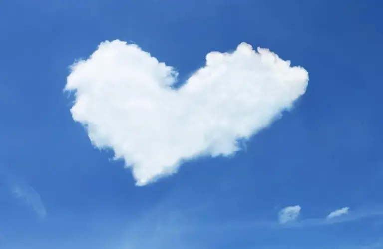image of A fluffy white cloud shaped like a heart floats against a clear blue sky, evoking a sense of calmness, whimsy, and Valentine's Day