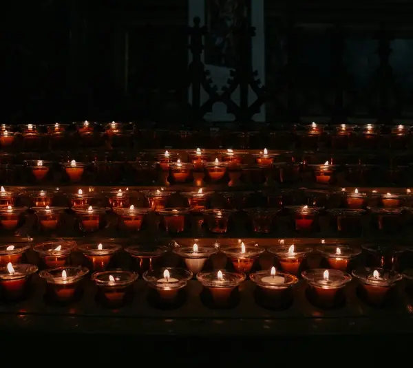 A warm cluster of lit candles glowing in a dark room, symbolizing the light and hope of Candlemas.