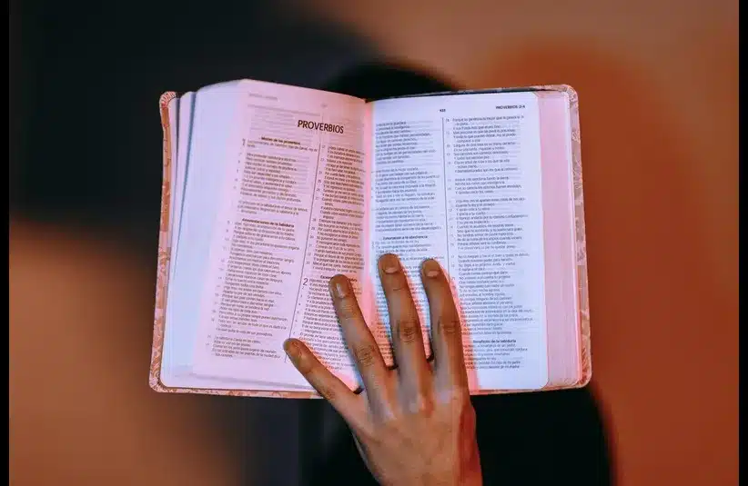 In Daily Devotion, a lady's hand is holding the Bible open to Proverbs, Genesis is at the beginning of the Bible.