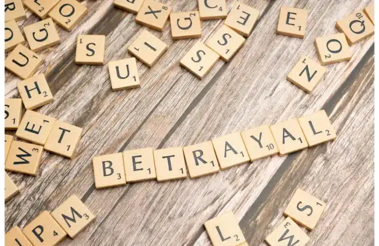 Wooden letter tiles spelling 'Betrayal' on a rustic wooden surface, conveying themes of deceit and dishonesty, representing cheating in relationships.